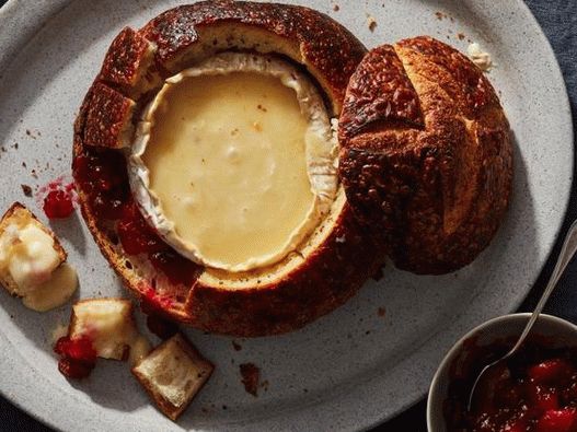 Foto Un bol de pan relleno de queso brie y salsa de arándanos