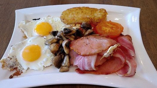 Foto desayuno irlandés con huevos fritos, croquetas de patata y tomates al horno