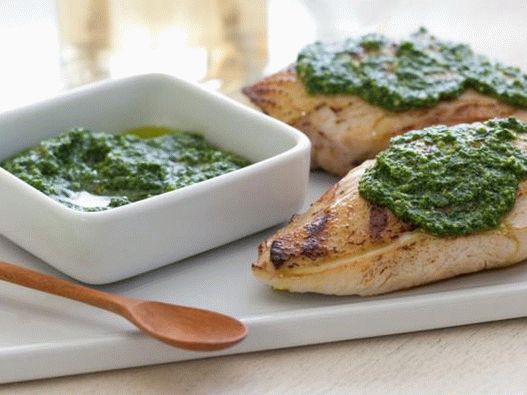 Pollo a la parrilla en una sartén con pesto de espinacas y piñones