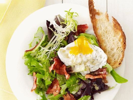 Ensalada con huevo escalfado y tocino en una cafetería